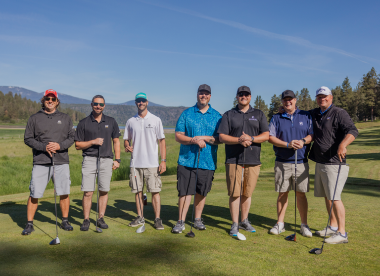 seven smiling men with golf clubs