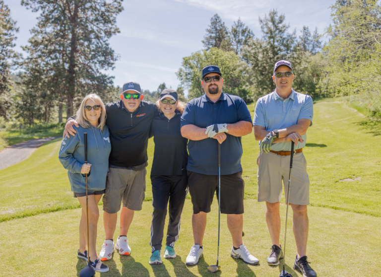 three men and two women with golf clubs